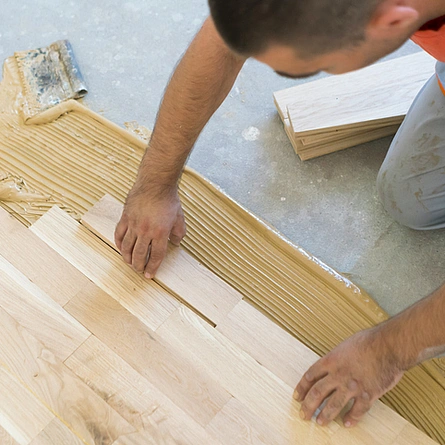 Handwerker verlegt und verklebt Parkett, Muster Schiffsboden oder gerader Verband - Handwerker verlegt und verklebt Parkett, Muster Schiffsboden oder gerader Verband